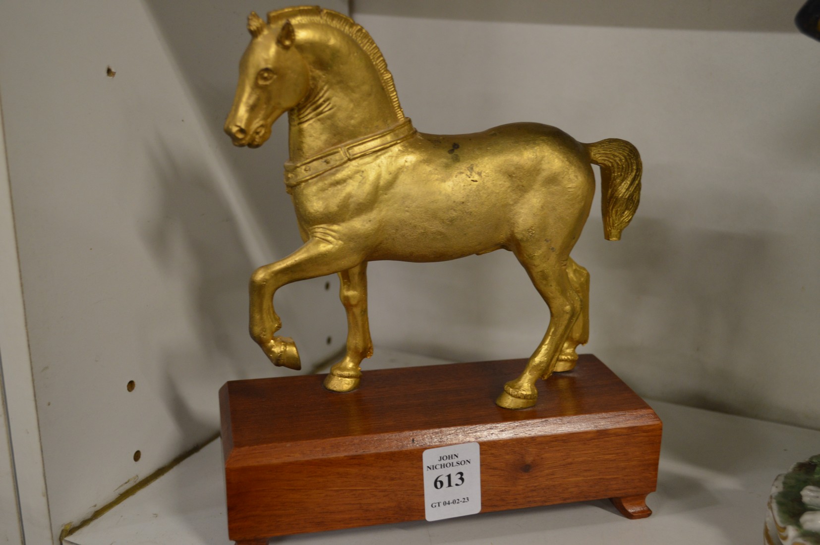 A gilded bronze model of a prancing horse on a wooden base.