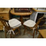 A pine circular kitchen table and two chairs.