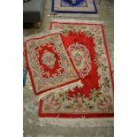 A red ground floral decorated rug and a similar smaller rug 5' x 3' and 3' x 2'.