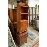 A narrow yew wood cupboard bookcase and a small chest of drawers.