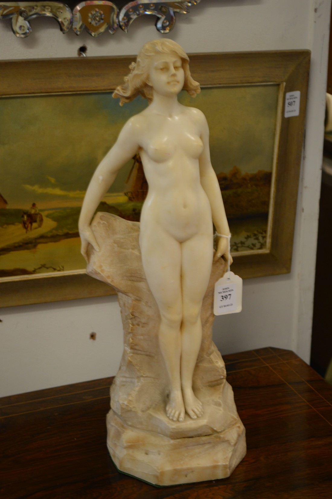 A good carved marble sculpture of a standing female nude on a rocky outcrop.