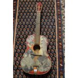 A classical guitar decorated with cut out news cuttings and photos of the Beatles etc.