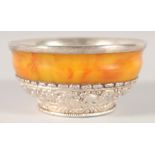 A TIBETAN SILVER MOUNTED AMBER BOWL, the interior with silver lining, 11cm diameter.