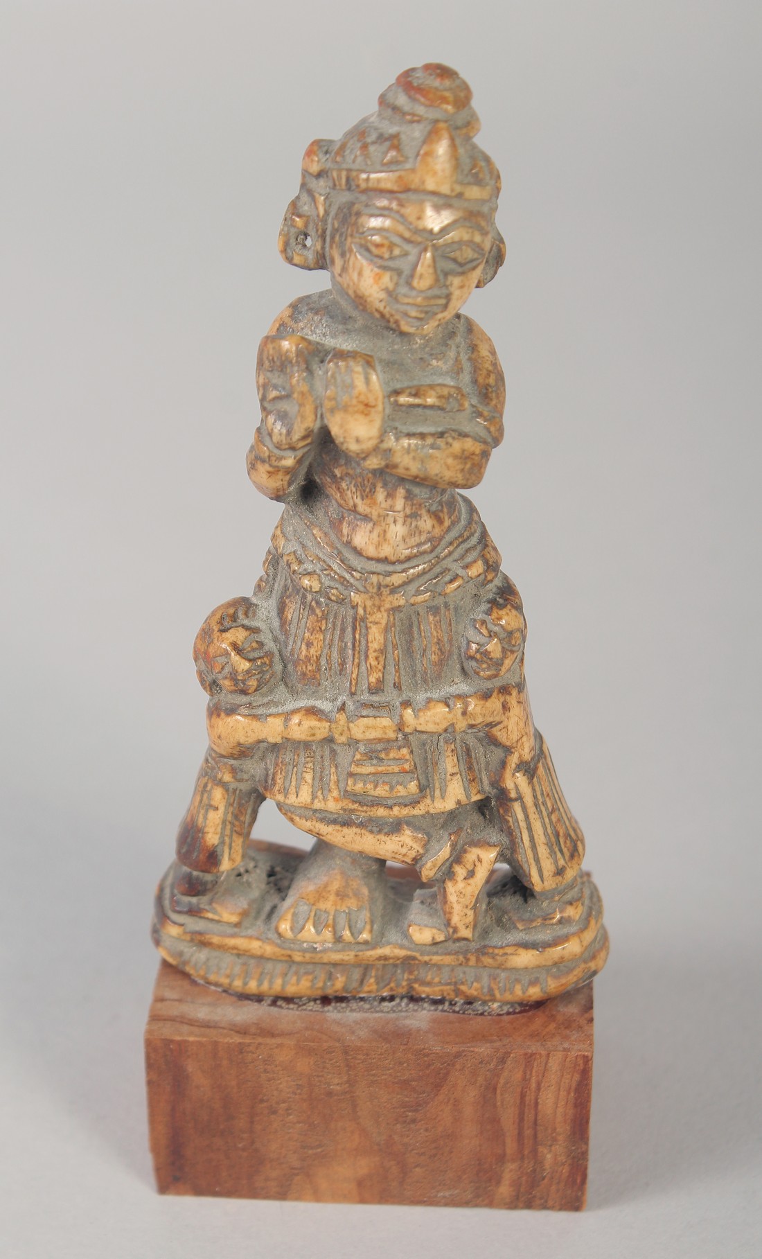A 17TH CENTURY SOUTH INDIAN CARVED BONE FIGURE of fluting Krishna, mounted to a wooden base, carving