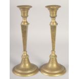 A PAIR OF ISLAMIC BRASS CANDLESTICKS, the bases with calligraphy, 31cm high.