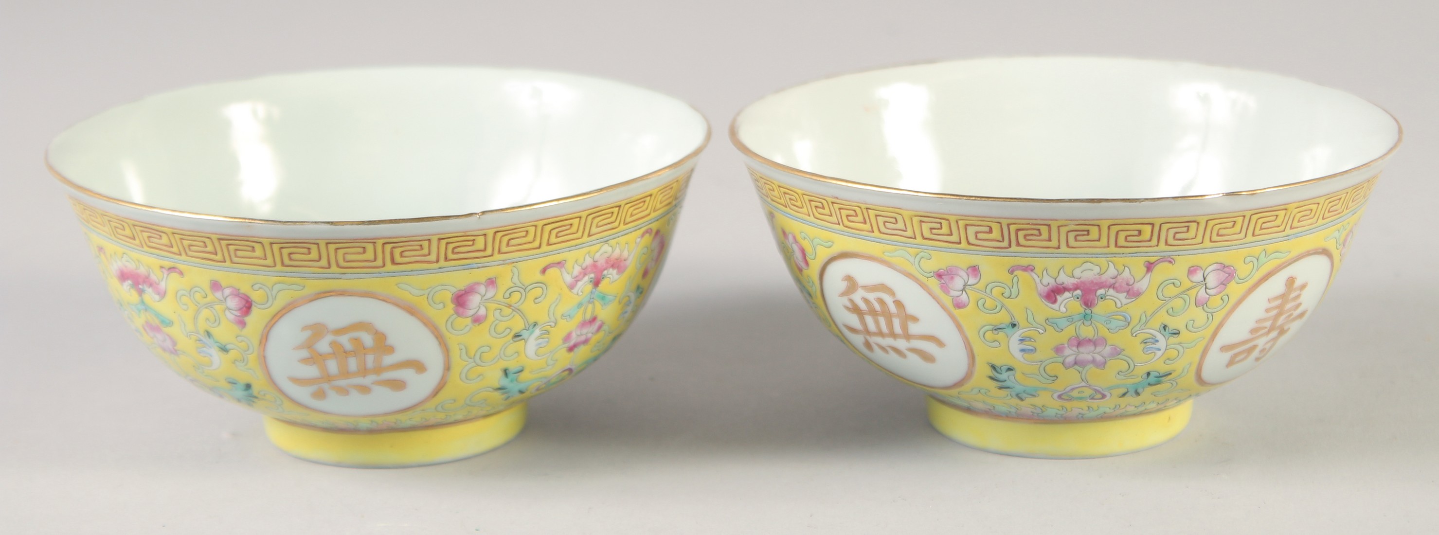 A PAIR OF CHINESE YELLOW GROUND FAMILLE ROSE PORCELAIN BOWLS, decorated with roundels of gilt