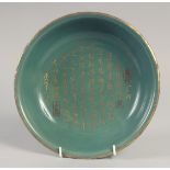 A CHINESE CELADON GLAZE DISH, with carved gilt characters, 23.5cm diameter.