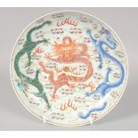 A CHINESE FAMILLE ROSE PORCELAIN PLATE, painted with dragons in coral red, blue and green, the
