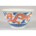 A CHINESE BLUE, WHITE AND IRON RED BOWL, with dragons and stylised clouds, Xuantong mark to base,
