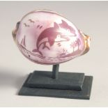 A COWRIE SHELL ON A STAND, engraved with dolphins. 2ins x 2.5ins