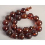 AN AMBER NECKLACE with twenty one ball beads. 15ins long.