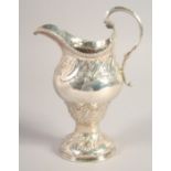 A LARGE III SILVER CREAM JUG with repousse decoration. London, 1768.