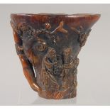 A GOOD CHINESE CARVED HORN LIBATION CUP carved with lotus and figures. 5.5ins.