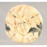 A CARVED BONE CIRCULAR FACES NETSUKE. 1.5ins diameter.