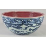 A CHINESE BLUE, WHITE AND COPPER RED BOWL decorated with dragons, six character mark to base. 27.5cm