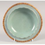 A CHINESE CELADON PETAL FORM DISH with incised gilt characters to the base. 20cm diameter.