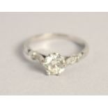A SOLITAIRE DIAMOND RING with diamond shoulders.