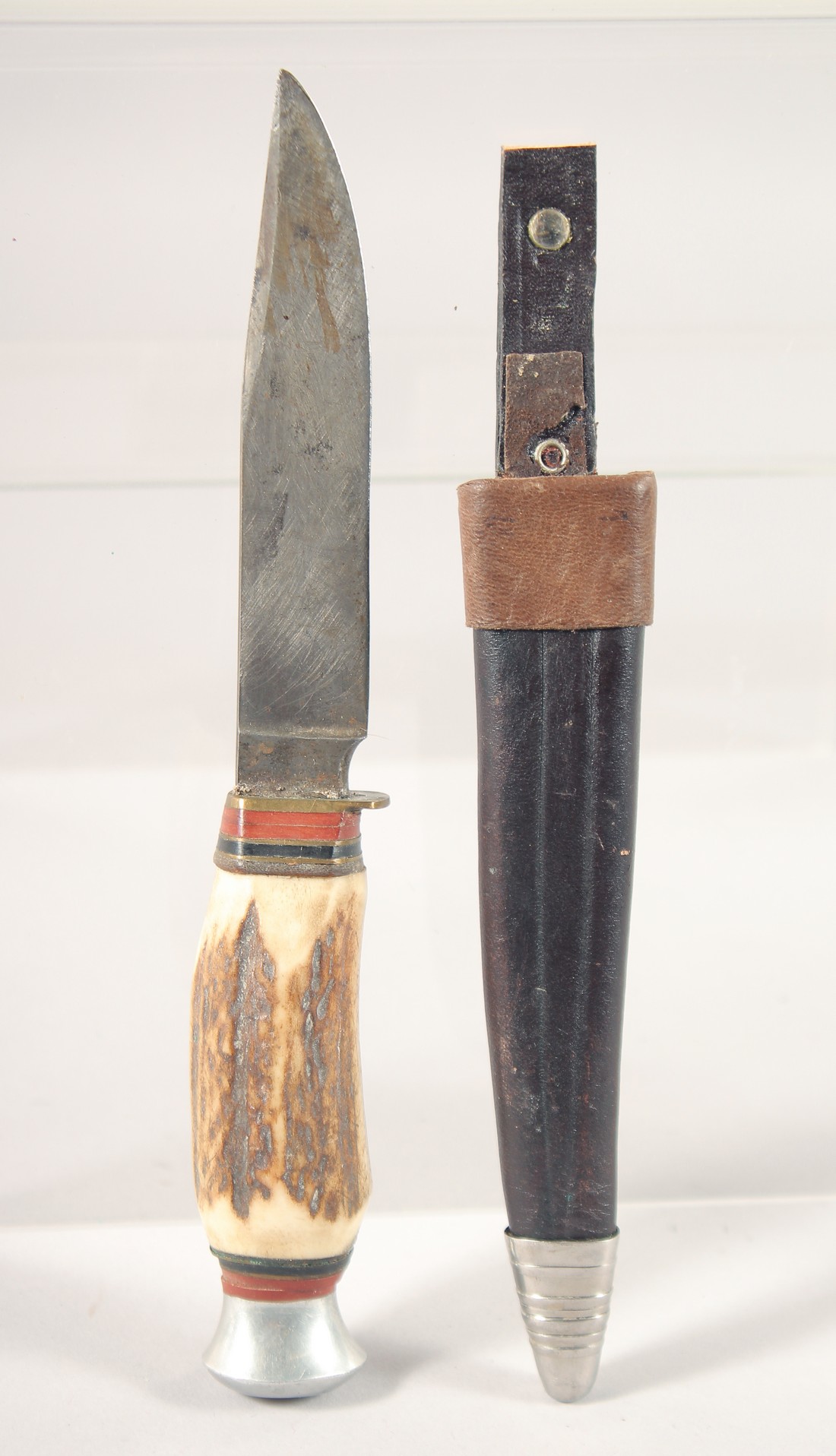 A PUMA KNIFE, with antler handle, in a leather sheath, 7.5" long.