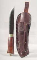 A KNIFE, with wooden handle, in a leather sheath, 11" long.