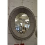 A grey painted oval wall mirror.