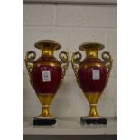 A pair of gilt decorated twin handled urn shaped vases.