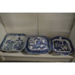A willow pattern vegetable dish and cover and two other similar dishes.