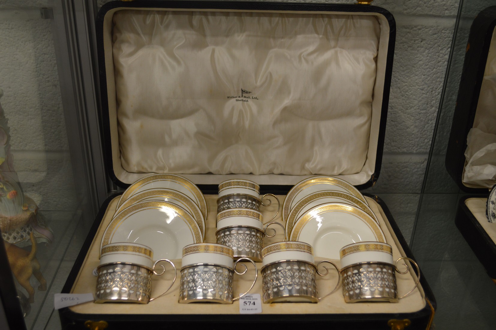 A Wedgwood cased set of six gilt decorated coffee cans and saucers with pierced silver holders.