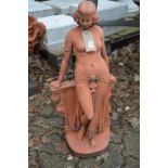A terracotta coloured garden sculpture of a classical standing female figure.