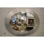 A silver framed oval wall mirror.