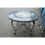 A wrought iron and composite circular garden table.