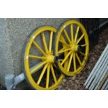 A pair of yellow painted wagon wheels.