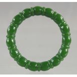 A RIBBED GREEN JADE BANGLE. 2.75ins diameter.