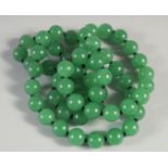A STRING OF SIXTY GREEN JADE BEADS. 25ins long.