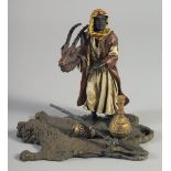 A COLD PAINTED BRONZE GROUP, an Arab man holding a deer's head and standing on a lion skin rug. 5.