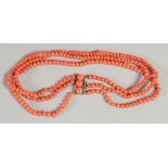 A THREE ROW CORAL NECKLACE with gold clasp.
