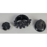 A WHITBY JET BRACELET AND TWO CARVED BROOCHES (3). 79gms.