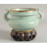 A CHINESE CELADON TWIN HANDLED CENSER AND STAND, the handles moulded as fish, characters to the