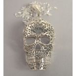 A SILVER FILIGREE SKULL PENDANT AND CHAIN.