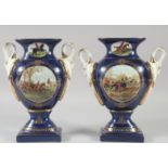 A PAIR OF CONTINENTAL BLUE TWO HANDLED HUNTING SCENES VASES. 11ins high.