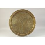 A LARGE EMBOSSED AND CHASED BRASS TRAY, depicting a mythological scene with animals, 59cm diameter.