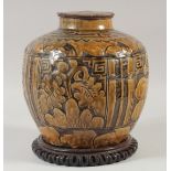 A CHINESE EARTHENWARE JAR AND COVER, with a carved hardwood stand, jar and cover, 25cm high.