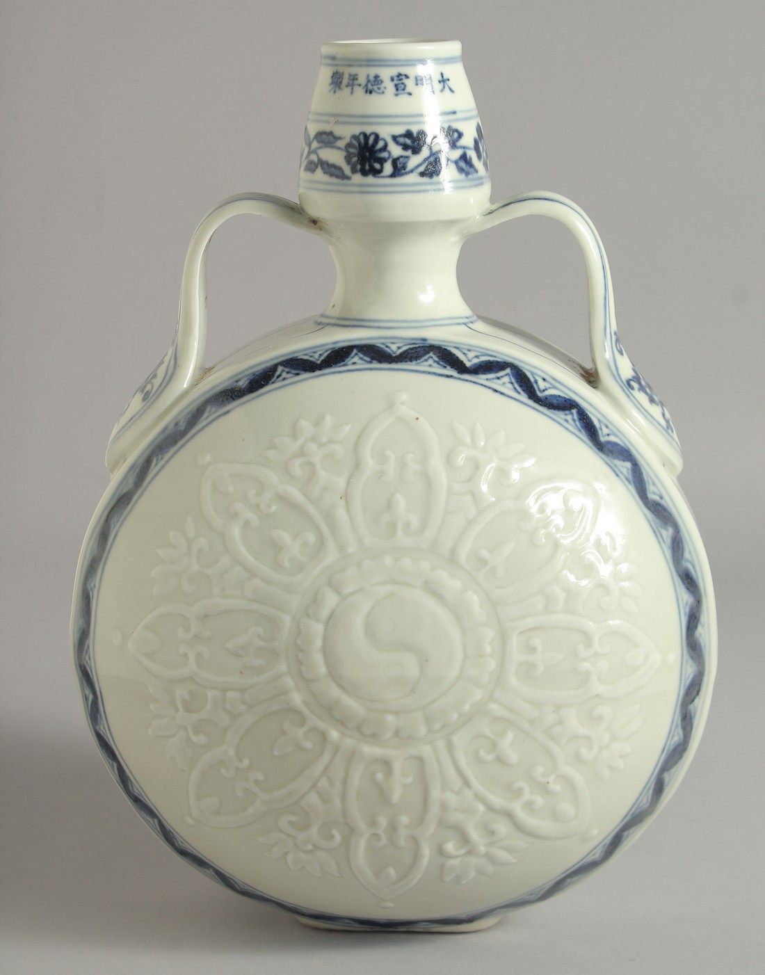 A CHINESE BLUE AND WHITE PORCELAIN TWIN HANDLED MOON FLASK, with carved yin-yang medallion radiating