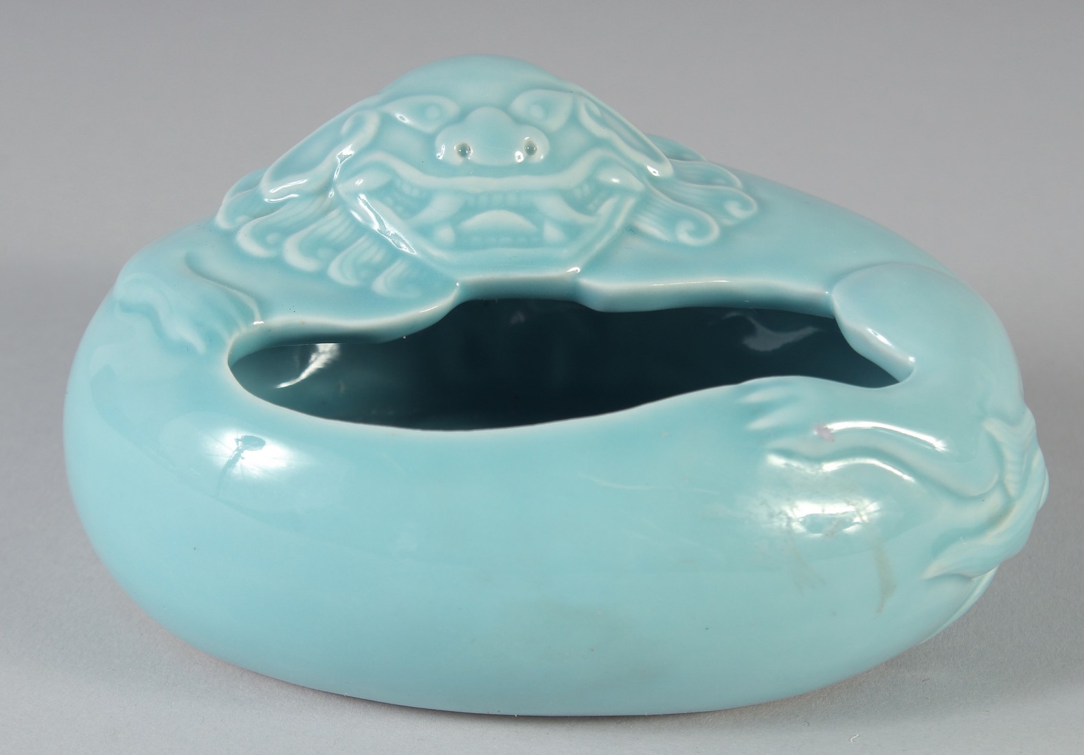 A CHINESE CLAIRE-DE-LUNE OVAL SECTION PORCELAIN BRUSH WASHER, moulded in relief with a Buddhistic