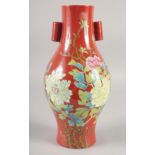 A CHINESE RED GROUND PORCELAIN TWIN HANDLE VASE, painted with flora, six-character mark to base,