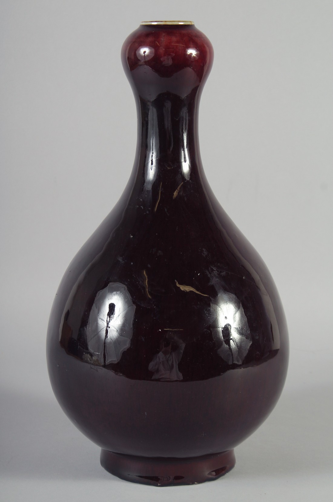 A CHINESE FLAMBE GLAZED PORCELAIN BOTTLE VASE, with a garlic neck, the sides applied with a dark
