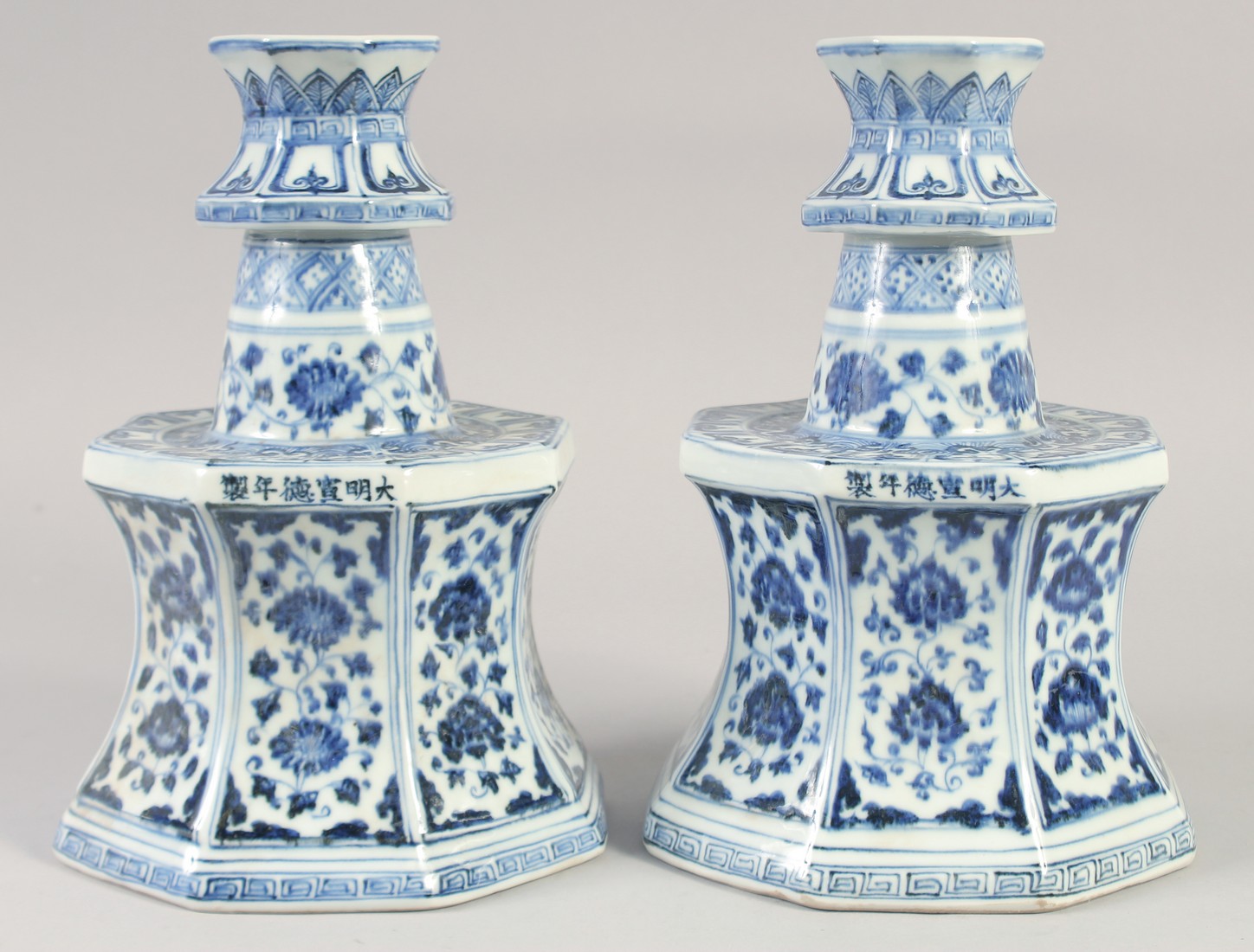 A PAIR OF A CHINESE BLUE AND WHITE PORCELAIN OCTAGONAL CANDLESTICKS, 27.5cm high.