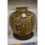 A large Chinese earthenware jar and cover on a hardwood stand.