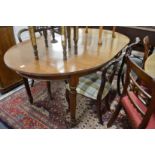 A mahogany extending dining table with a central leaf on reeded turned legs.