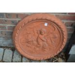 A circular terracotta plaque decorated with cherubs.