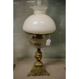 An ornate brass and glass oil lamp with opaque glass shade.